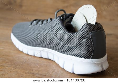 Gray running shoes with orthopedic insoles. Wooden board