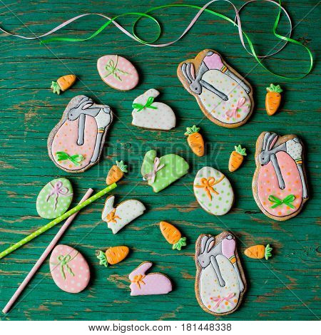 Easter gingerbread cookies in the shape of hares and carrots on a green background