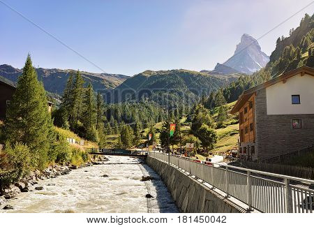 Zermatt, Switzerland - August 24, 2016: Traditional Swiss chalets and Gornera River in resort city Zermatt with a view on Matterhorn peak in Switzerland in summer
