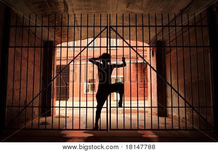 Silhouette der tanzenden Mädchen im Dunkeln, sie klettern auf Latice mit angehobenen Bein in der Mitte des Gitters