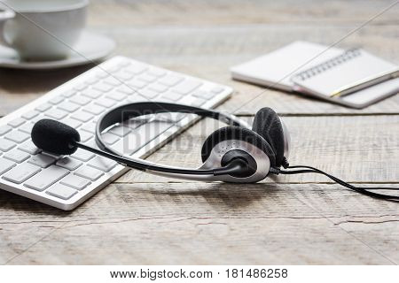 operator headset and computer keyboard on workdesk for call center concept on wooden background