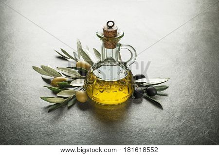 Olive oil and olive branch on the gray table