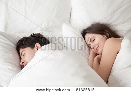 Young woman and man lying asleep in cozy big white bed at home under blanket, soft sleep, couple sleeping together with smiles on their faces, lovers do not want to wake up in the morning