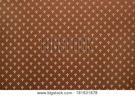 Brown textile background with royal lily or fleur-de-lis pattern on cloth texture