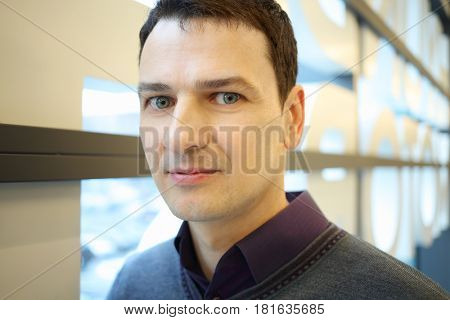 Happy handsome brunet man poses in shopping center, close up