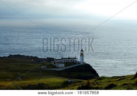 Scotland's Neist Point lighthouse with rolling hills and cliffs.