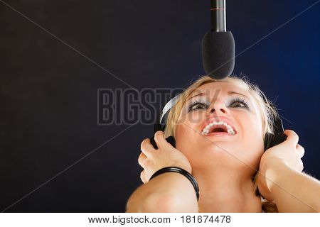 Woman Singing To Microphone Wearing Headphones In Studio