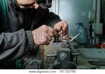 Mechanics repairing a diesel injector. Man disassemble a injector pinched in a vise.