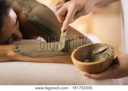 Closeup of applying mud mask with hands of professional therapist.