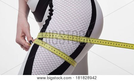 Time for diet slimming weight loss. Fitness woman fit girl in sportswear with measure tape measuring her thigh on white