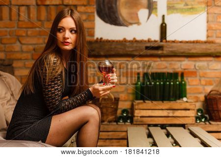 Woman Tasting Wine In Rural Cottage Interior