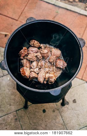 Cooking plov in the cauldron. Only the meat in the cauldron. Field kitchen. Eastern cuisine.