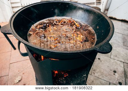 Cooking plov in the cauldron. Only meat, onions and carrots in the cauldron. Field kitchen. Eastern cuisine.