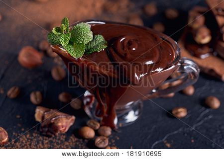 Homemade hazelnut spread or hot chocolate in glass bowl with nuts and chocolate bar. Cocoa powder nuts and chocolate background. Confectionery and sweets concept.