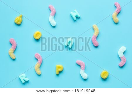 Colorful candies scattered on blue texture background top view mock up