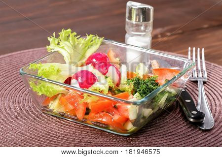 Fresh vegetables salad in a glass bowl. Mix from the cut radish pomidory and cucumbers. Close up selective focus