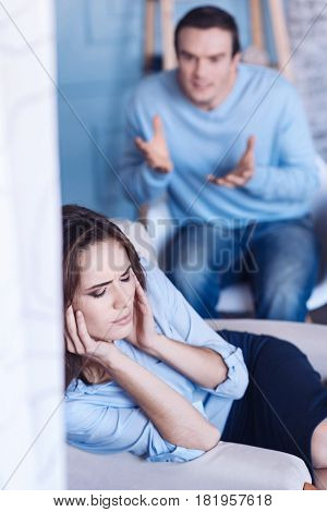 I am not listening. Unhappy sad cute woman closing her eyes and covering her ears while having an argument with her boyfriend