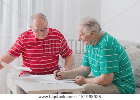 Two elderly men with documents on sofa