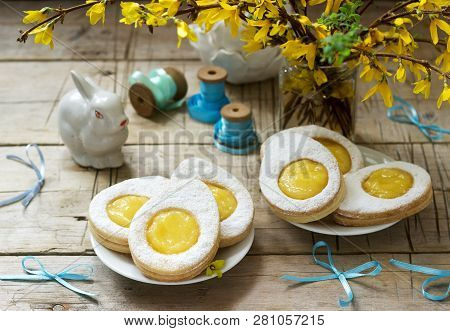 Easter Composition With Egg-shaped Cookies Filled With Lemon Curd, Rabbit, Bouquet Of Forsythia And 
