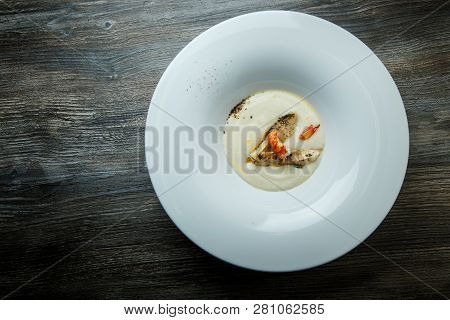 White Fish Cream Soup Decorated With Fried Pieces Of Fish, Prawn, And Spices