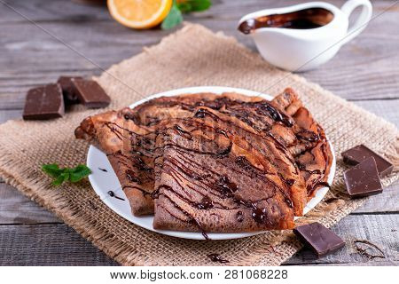 Homemade Pancakes Or Russian Blini With Chocolate Sauce On Plate On Rustic Wooden Background