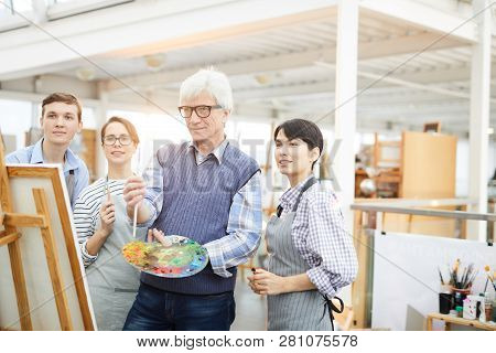 Portrait Of Mature Art Teacher Enjoying Work With Group Of Students In Art Class, Copy Space