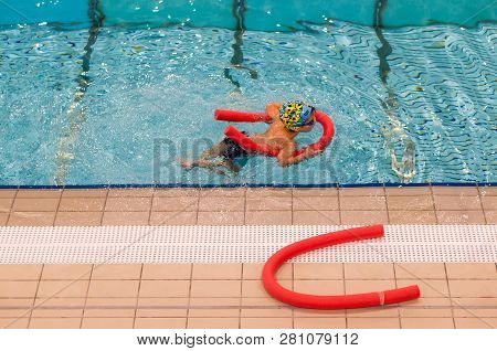 Poznan, Poland - January 26, 2019: Boy Swimming With Help Of A Red Stick During Lesson In The Termy 