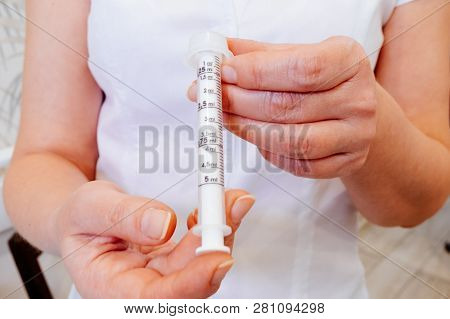 A Young Woman Doctor Distributes Portions Of Drugs In The Hospital, Determining Each Put Milliliters