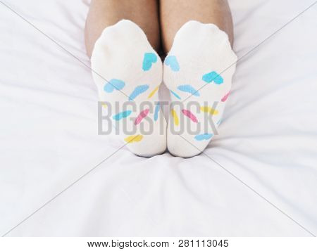 Close Up Woman Feet Wearing White Sock With Pastel Heart Shape Pattern On Bed In Bedroom. Love Conce