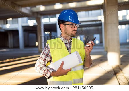 Male Architect Communicating On Walkie-talkie At Site