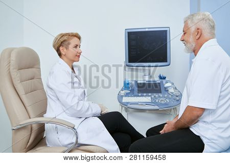 Portrait Of Two People In Hispital On Medical Observation. Elderly Man Sitting And Talking With Prof