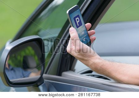 Driver using smartphone app to pay for parking in the paid parking zone in a city