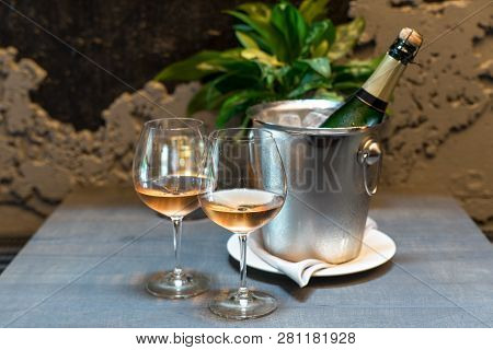 Two Cold Glasses Of Sparkling Wine. The Wall Ow Wine Bottels On Background.
