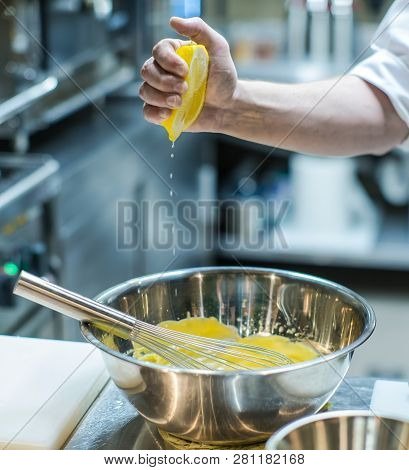 Kitchen In The Restaurant. Chef Is Preparing A Yellow Sauce. Squeezes Juice From A Lemon.
