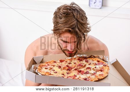 Food Delivery Service. Portrait Of Lazy Muscular Man Eating Pizza While Laying On A Bed At Home. Man