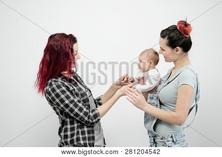 Two Young Women With A Baby On A White Background. Same-sex Marriage And Adoption, Homosexual Lesbia