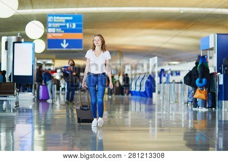 Young Woman In International Airport Walking With Luggage, Ready For Her Flight