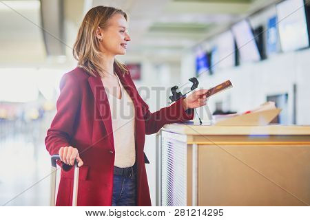 Young Woman In International Airport At Check-in Counter Giving Her Passport To Officer