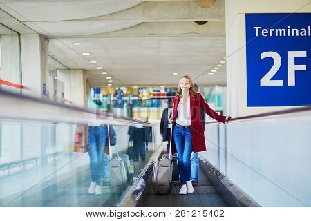 Young Woman In International Airport With Luggage On Travelator