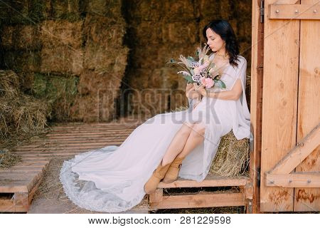 Portrait Of Bride In Style Of Boho, Which Sits In Hayloft