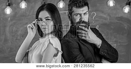 Man With Beard And Teacher In Eyeglasses Stand Back To Back, Chalkboard On Background. Teacher And S