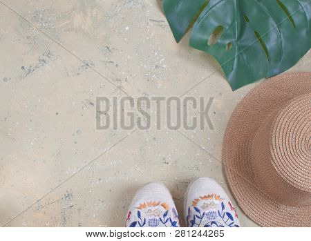 Minimalistic Summer Flat Lay With Women Espadrilles, Summer Hat And Monstera Leaf On Soft Yellow Bac