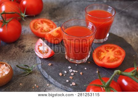 Two Glasses Of Tomato Juice, Bunch Of Tomatoes And Pink Salt On Dark Background
