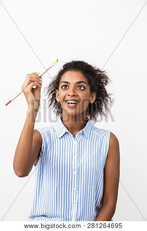 Beautiful young african woman atrist holding a paint brush over white background