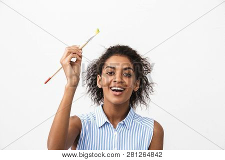 Beautiful young african woman atrist holding a paint brush over white background