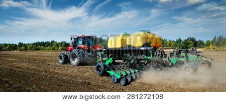  Modern, green tractor in the spring field work on the background of a beautiful rural landscape.