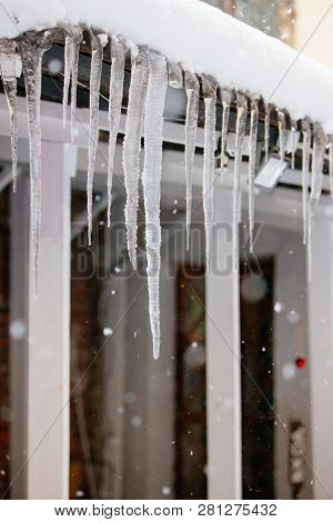 Roof Covered With Sharp Icicles. Ice Stalactite Hanging From The Roof During A Snowfall. Poor Therma