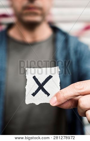 closeup of a young caucasian person holding a piece of paper with a X written in it, for the third gender category