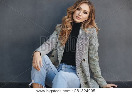 Portrait Of Beautiful Woman With Long Curly Blond Hair On Gray Background. Young Woman With Natural 