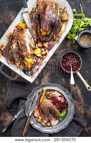 Traditional barbecue pheasant with vegetable and cranberry sauce as top view in a stewpot and on a plate 